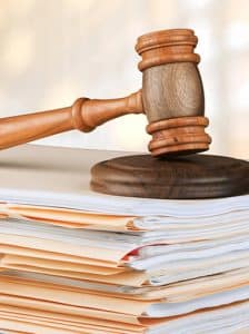 The Benefits of Estate Planning is choosing who has power of attorney over your estate. The image is a gavel on a stack of files.
